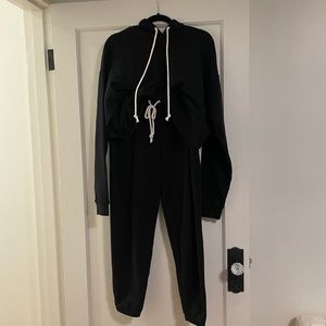 Black sweatsuit hoodie and pants with white string detail.